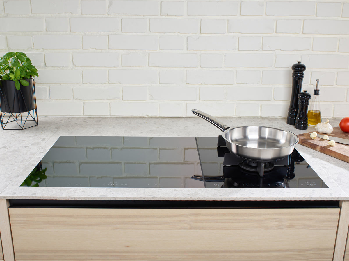 Eine moderne Küche mit Fissler Ceratal Classic und Pure Pfanne auf einem Induktionskochfeld, die deutsche Qualität und Design zeigt.