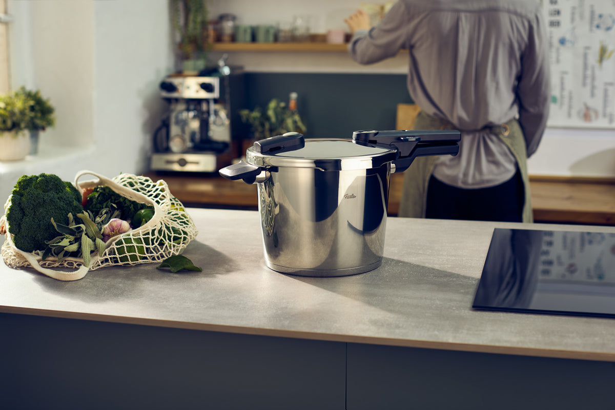 Fissler Vitaquick® Elemental 3-tlg. Schnellkochtopf-Set auf der Theke, in der Nähe von frischem Gemüse-präzises deutsches Kochgeschirr seit 1845.