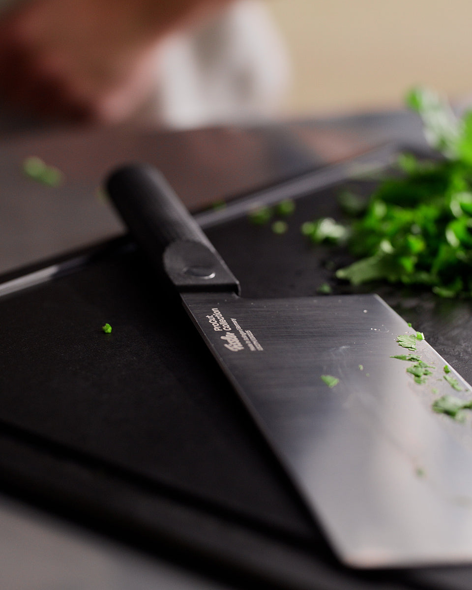 Fissler ProCut Chinese Chef's Knife 18cm - timeless design, precision-crafted, on a cutting board with herbs and garlic nearby.