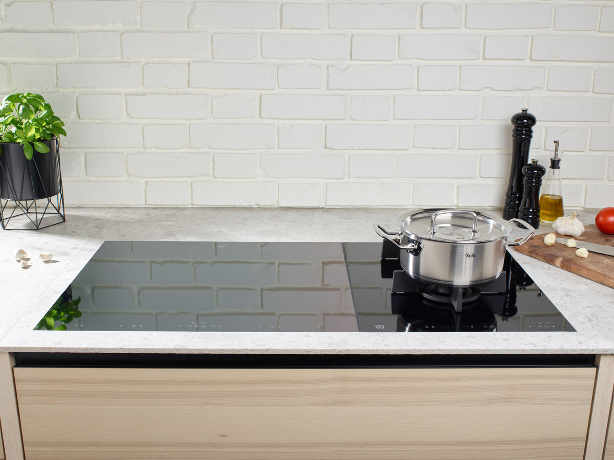 A modern kitchen with the 5-piece stainless steel set from the Fissler Original-Profi Collection®, herbs, and accessories - timeless German quality.