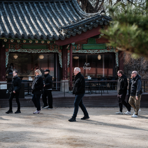 Eine Gruppe von Menschen geht an einem traditionellen koreanischen Gebäude vorbei, an dem ein Schild mit der Aufschrift „Art Shop“ hängt. Die kunstvollen Holzdetails und das Ziegeldach des Gebäudes spiegeln eine lange Tradition handwerklicher Kunst wider – ein Ethos, das auch Fissler teilt, wo Präzisionstechnik und zeitloses Design jeden von uns hergestellten Edelstahltopf, jede Pfanne und jeden Schnellkochtopf prägen.