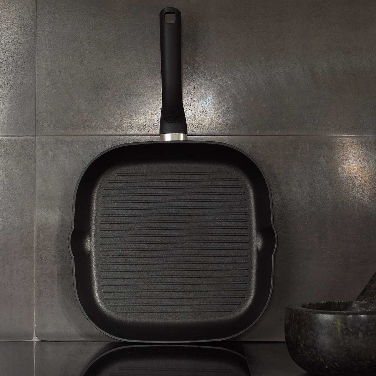 Die Fissler Cenit® Grillpfanne Induktion 28 cm steht aufrecht und besticht durch deutsches Design, moderne Grate und einen langen Griff.