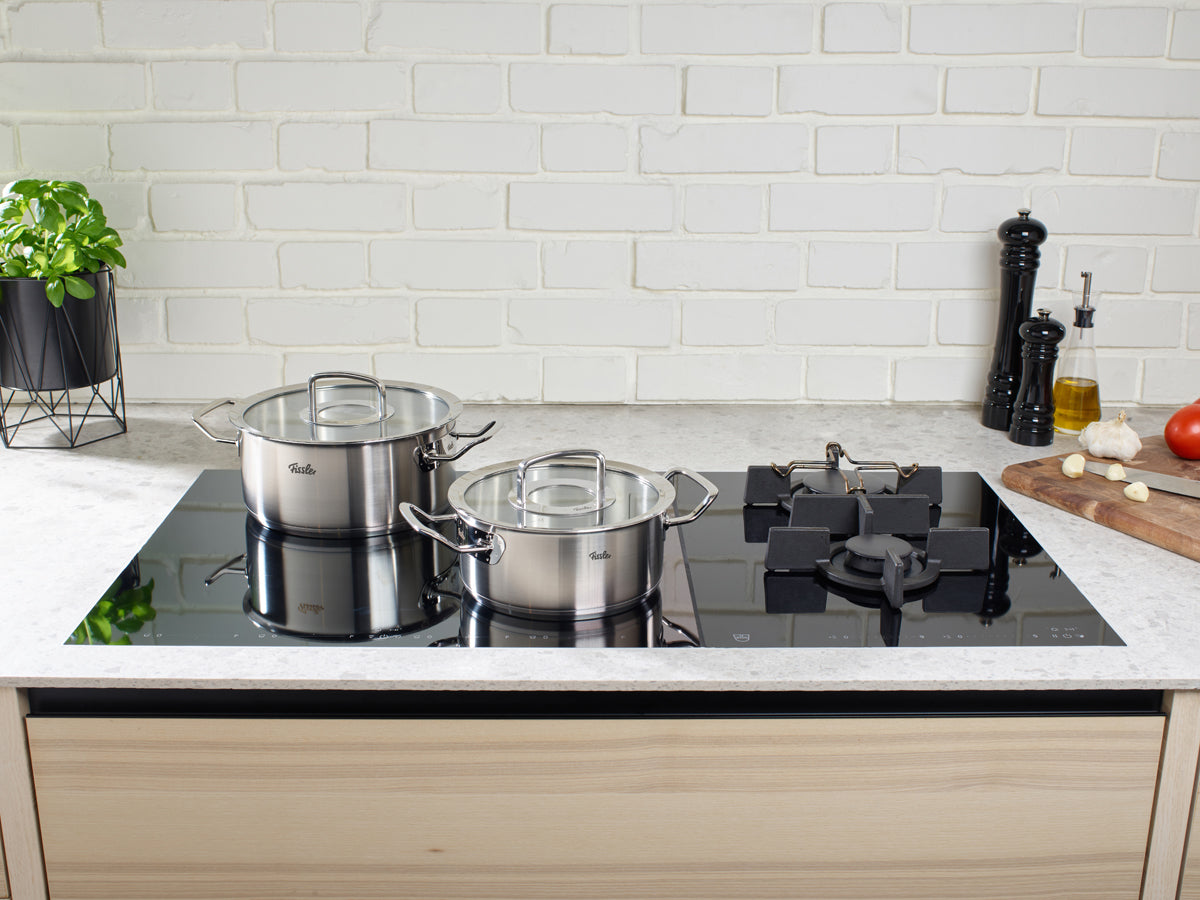 Eine moderne Küche mit zwei Fissler Original-Profi Collection® Bratentopf mit Glasdeckel auf einem eleganten schwarzen Glas-Kochfeld.