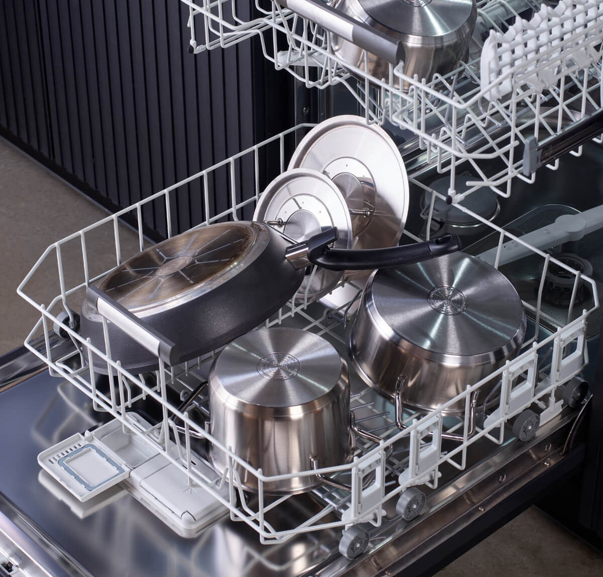 Offener Geschirrspüler mit Fissler Adamant® Comfort 2-teiligem Pfannenset, kratzfest, in moderner Küche mit schwarzen, metallischen Akzenten.