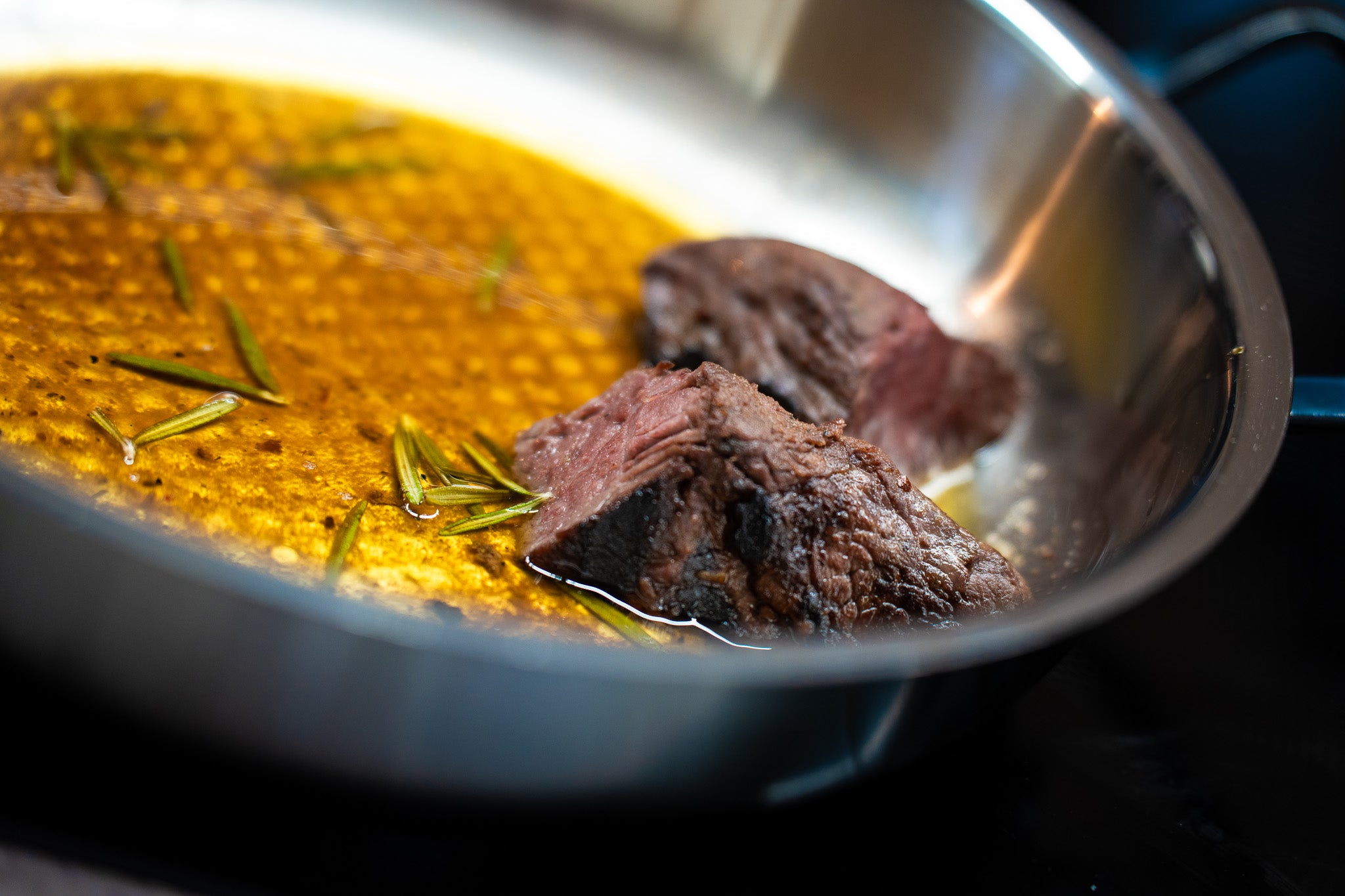 Perfekt gebratenes Fleisch mit Rosmarin in goldbrauner Sauce, präsentiert in einer hochwertigen Fissler-Edelstahlpfanne.