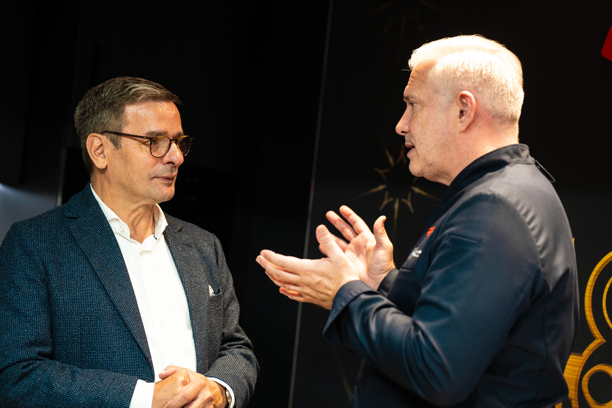 Zwei Männer diskutieren in einer modernen Küche; auf dem Tresen daneben steht hochwertiges Fissler-Edelstahl-Kochgeschirr.