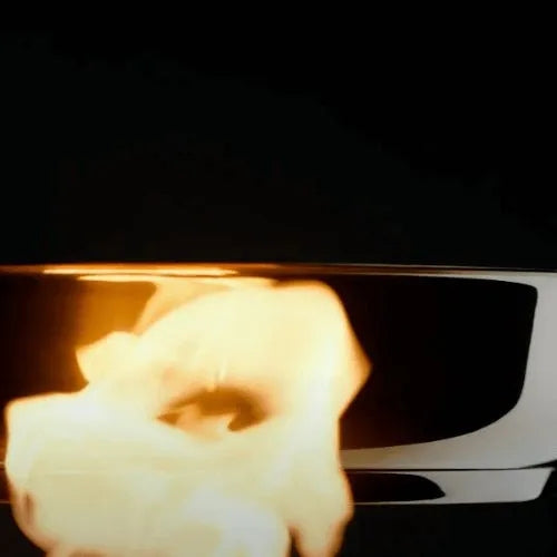 Eine Nahaufnahme einer Fissler-Edelstahlpfanne mit leuchtenden Flammen, die deutsche Präzision und Langlebigkeit vor einem dunklen Hintergrund demonstriert.